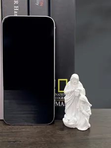 Macro detail of compact white resin Nativity scene figurines next to a smartphone