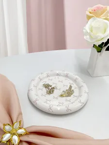 Detailed view of elegant gold brooches with rhinestones and pearls on a ceramic bow tray