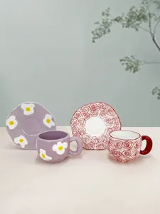 Detail of handmade ceramic coffee cup and saucer set with floral patterns and irregular edges