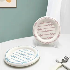 Hand-painted ceramic dessert plates with pink and blue bow patterns and thick edges