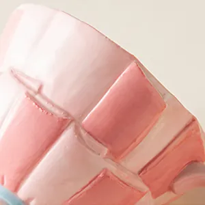 Makroaufnahme einer handgeformten rosa karierten Keramiktasse mit Glasurtextur