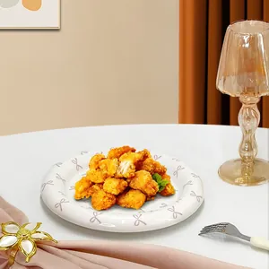 Ceramic dessert plate with purple bow patterns holding fried chicken in cozy home setting