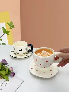 Detail of handmade ceramic cup with cherry pattern and wavy saucer for afternoon tea