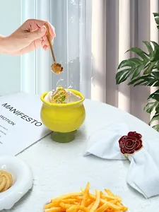 Détail d'un rond de serviette rose rouge avec cuillère dorée et bol citron jaune