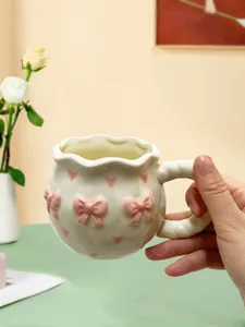 Vue détaillée d'une jolie tasse à café en céramique avec des nœuds roses et des cœurs pour le goûter.
