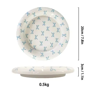 Ceramic dessert plate with blue bow patterns showing top and side views for dimensions