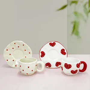 Handmade ceramic coffee cup and saucer sets with heart patterns on a minimalist tabletop
