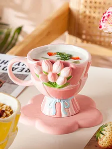 Detailansicht der rosa Keramik-Tulpentasse mit floraler Untertasse auf einem Holzstuhl