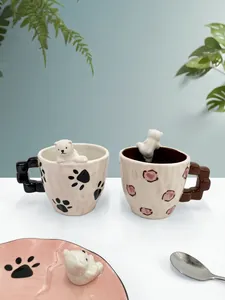 Dettaglio di tazze da caffè in ceramica con orsetto 3D e piattini coordinati neri