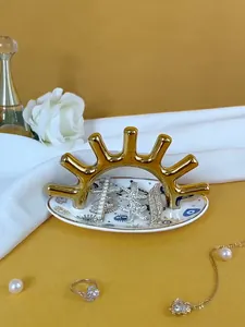 Detalle de bandeja para joyas con ojo turco, soporte dorado y fondo de satén