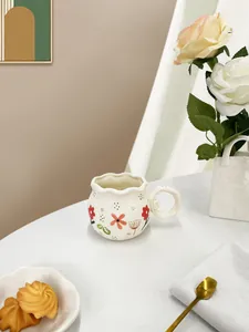 Detailed macro of a handmade ceramic coffee mug with floral patterns and a wavy rim