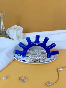 Detalle del soporte azul para joyas con ganchos de arco y bandeja cerámica con flores