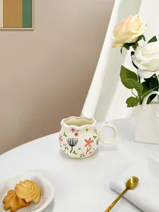 Detail of floral ceramic mug with wavy rim and spiral handle on an afternoon tea table