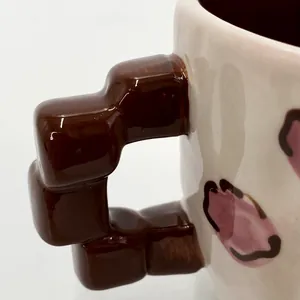 Dettaglio di tazza in ceramica con particolare manico geometrico a cubi marroni