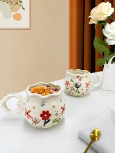 Close-up of hand-painted floral ceramic coffee mug with unique scalloped rim and handle