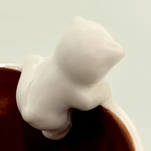 Macro di un simpatico orso polare in ceramica 3D appeso al bordo di una tazzina da caffè