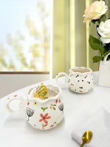 Detail of cream ceramic mug featuring a wavy rim and colorful hand-painted flowers