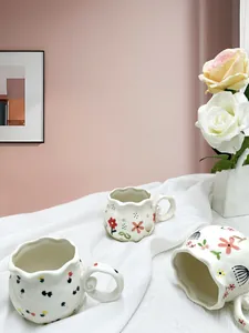 Detailed view of floral ceramic mugs with wavy rims and hand-painted petal patterns