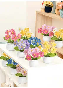 Close-up of handmade crochet forget-me-not flowers in white ceramic pots with vibrant colors