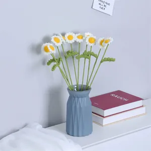 Ramo de margaritas tejidas a mano en jarrón azul para decoración creativa del hogar
