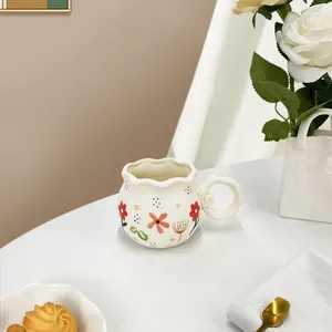 Floral ceramic coffee mug with wavy rim and hand-painted flowers on marble surface
