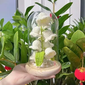 Detailed view of hand-crocheted lily of the valley lamp held against a green background