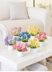 Detailed handmade crochet forget-me-not potted plants on a white marble table
