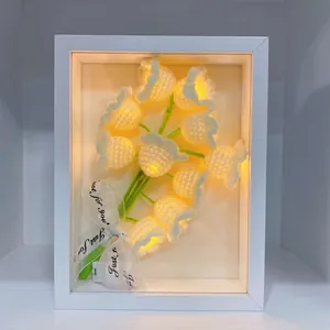 Detail of hand-crocheted lily of the valley night light in a minimalist white frame