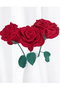 Detail of three handmade crochet red roses in a white ceramic vase with clear knit textures