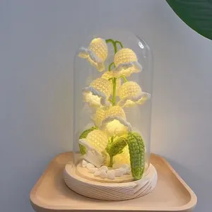 Close-up of handmade lily of the valley night light with crochet flowers in glass dome