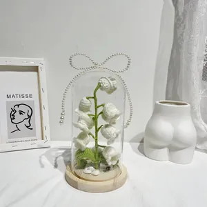 Macro view of handmade crochet lily of the valley lamp with wood base and glass dome