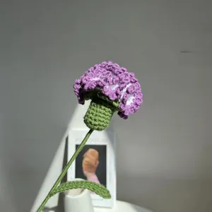 Dettaglio di un garofano fatto a mano all'uncinetto viola con stelo in maglia verde