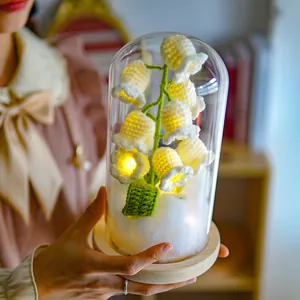 Close-up of handmade lily of the valley night light with warm LED glow in a glass dome