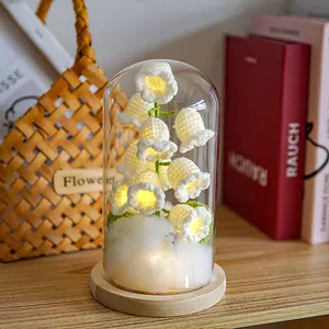 Detailed view of hand-crocheted lily of the valley lamp with warm LED in a glass dome