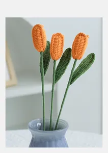 Detailed view of three handmade crochet orange tulips in a blue glass vase decor