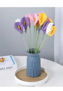 Macro detail of handmade crochet calla lily bouquet with textured yarn in a blue vase