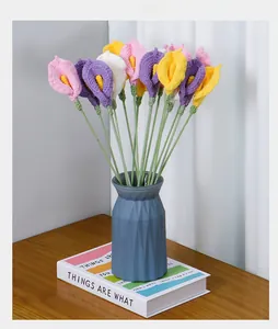 Handmade crochet Calla Lilies in colorful yarn displayed in a textured blue vase