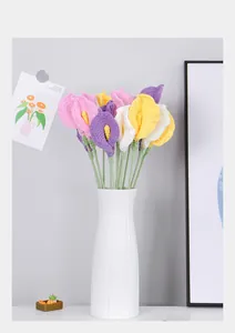 Close-up of handmade crochet calla lily bouquet in a striped white ceramic vase