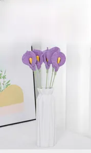 Close-up of five handmade crochet purple calla lilies in a white ceramic vase