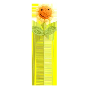 Dettaglio ravvicinato di un girasole all'uncinetto fatto a mano con faccina e foglie verdi