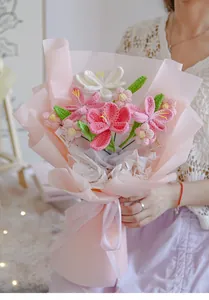 Detail of handmade crochet flower bouquet with lilies and daisies in soft pink wrapping