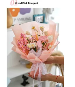 Close-up of hand holding a hand-knitted pink lily and daisy bouquet in gift wrap