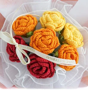 Detailed close-up of six handmade crochet roses in red and yellow with gift packaging