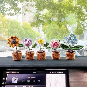 Detail of five handmade crochet flower pots including sunflower and tulip on car dashboard