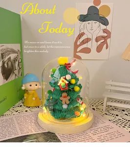 Handmade knitted Christmas tree with LED lights in a glass dome on a wooden base