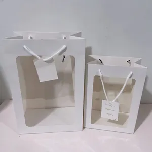 Detail von weißen Geschenktüten mit Sichtfenster und weißen gewebten Tragegriffen