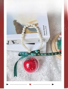 Close-up of a handmade knitted apple inside a clear bauble with white pearl handle