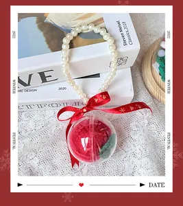 Detail of a handmade knitted red apple inside a clear festive bauble with pearl handle