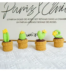 Set of four handmade crochet cactus plants with small yellow flowers in woven pots
