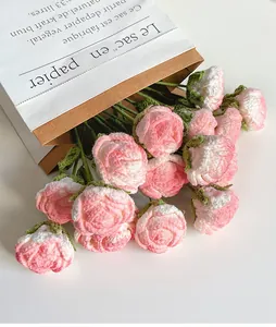 Close-up of handmade pink and white crochet roses with soft wool texture and green stems